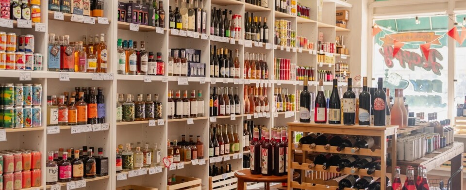 The interior of a bottle shop with shelves stacked with bottles and cans of beverages. 