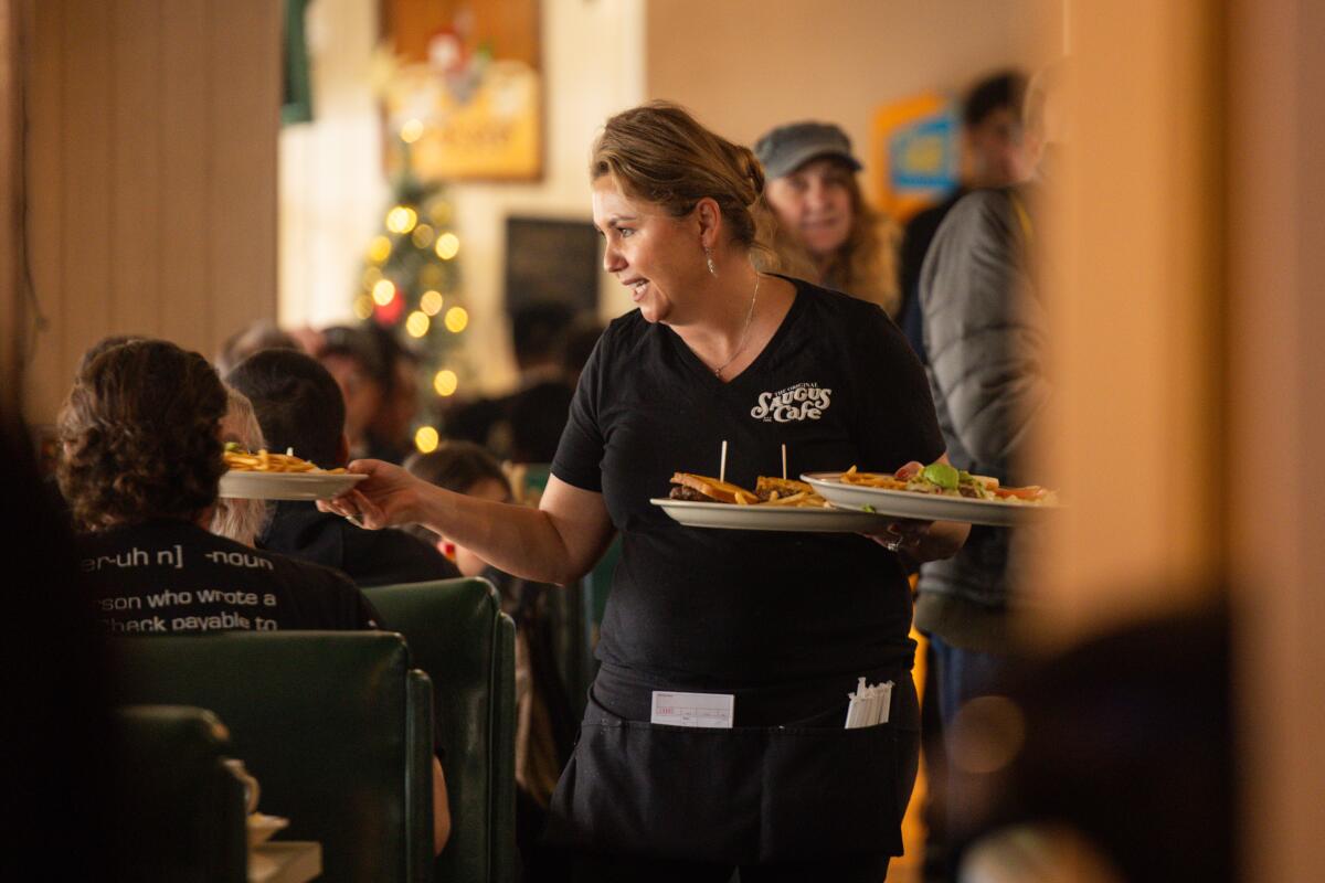 A woman carries plates of food.