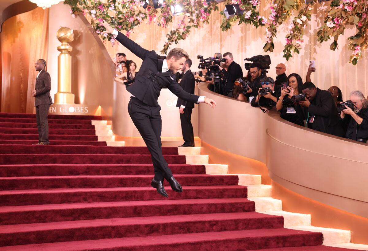 Derek Hough leaps in the air over steps on the Golden Globes red carpet 
