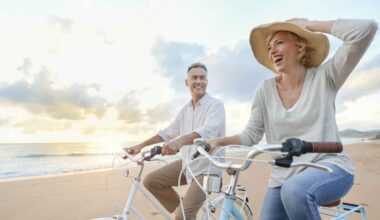 Mature couple cycling on the beach at sunset or sunrise.