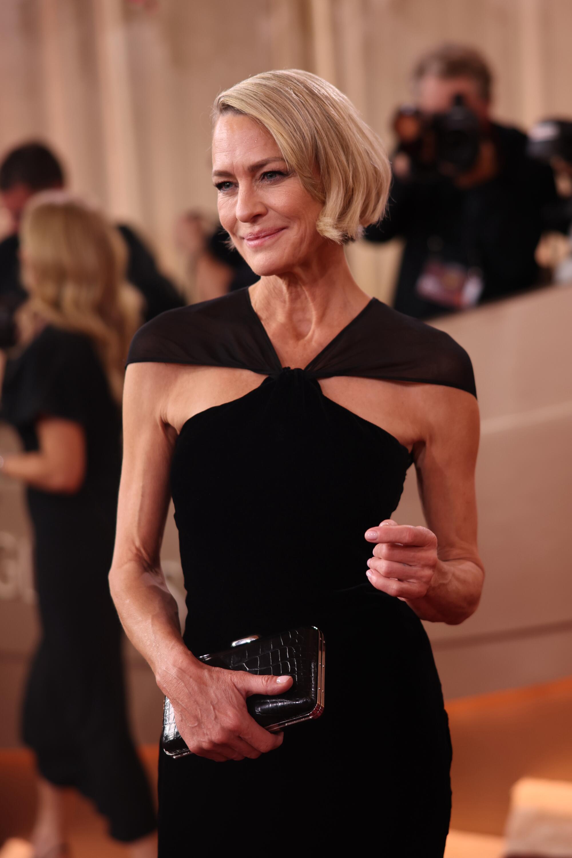 Robin Wright, wearing a black gown, walks the red carpet. 