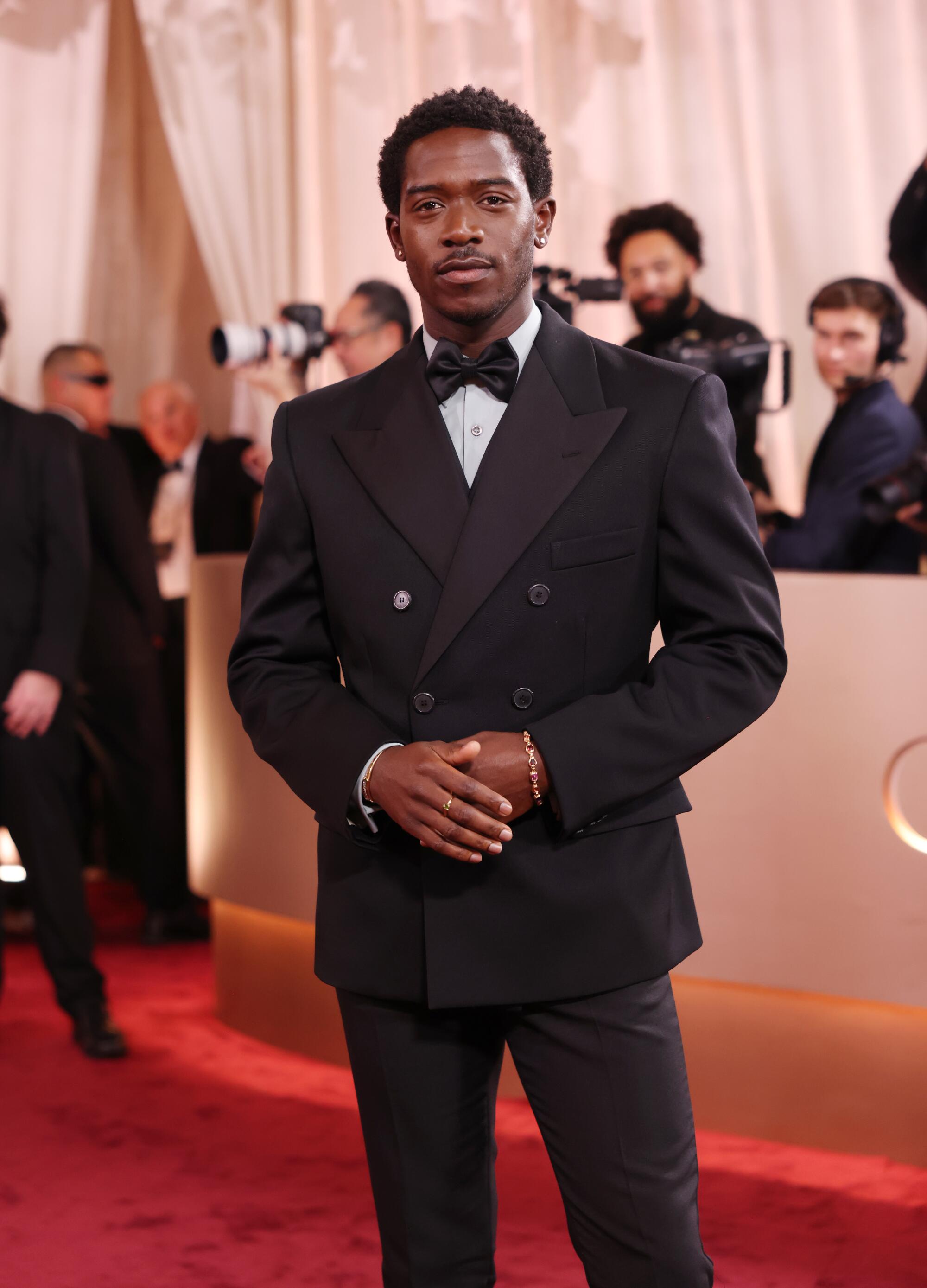 Damson Idris, in a black tux, poses on the red carpet. 
