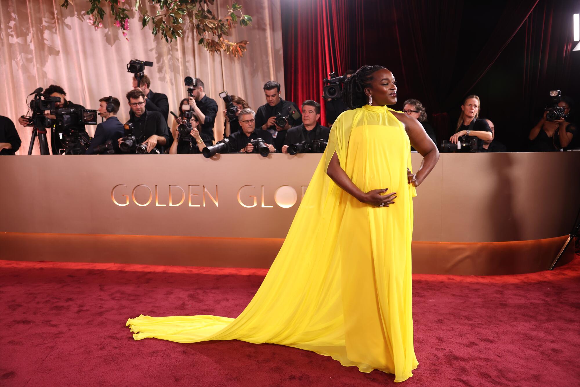  Wunmi Mosaku, in a yellow gown, walks the red carpet. 