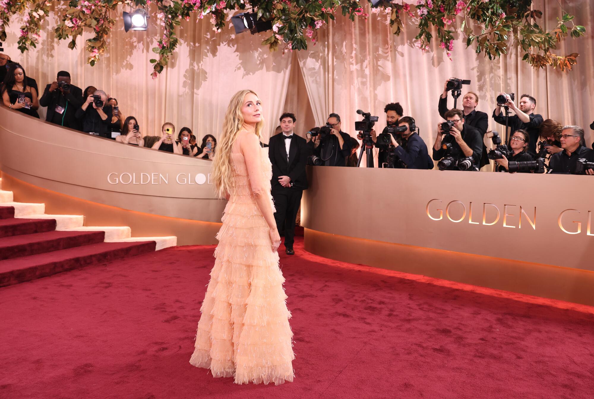 Justine Lupe, in a sheer dress, walks the red carpet. 