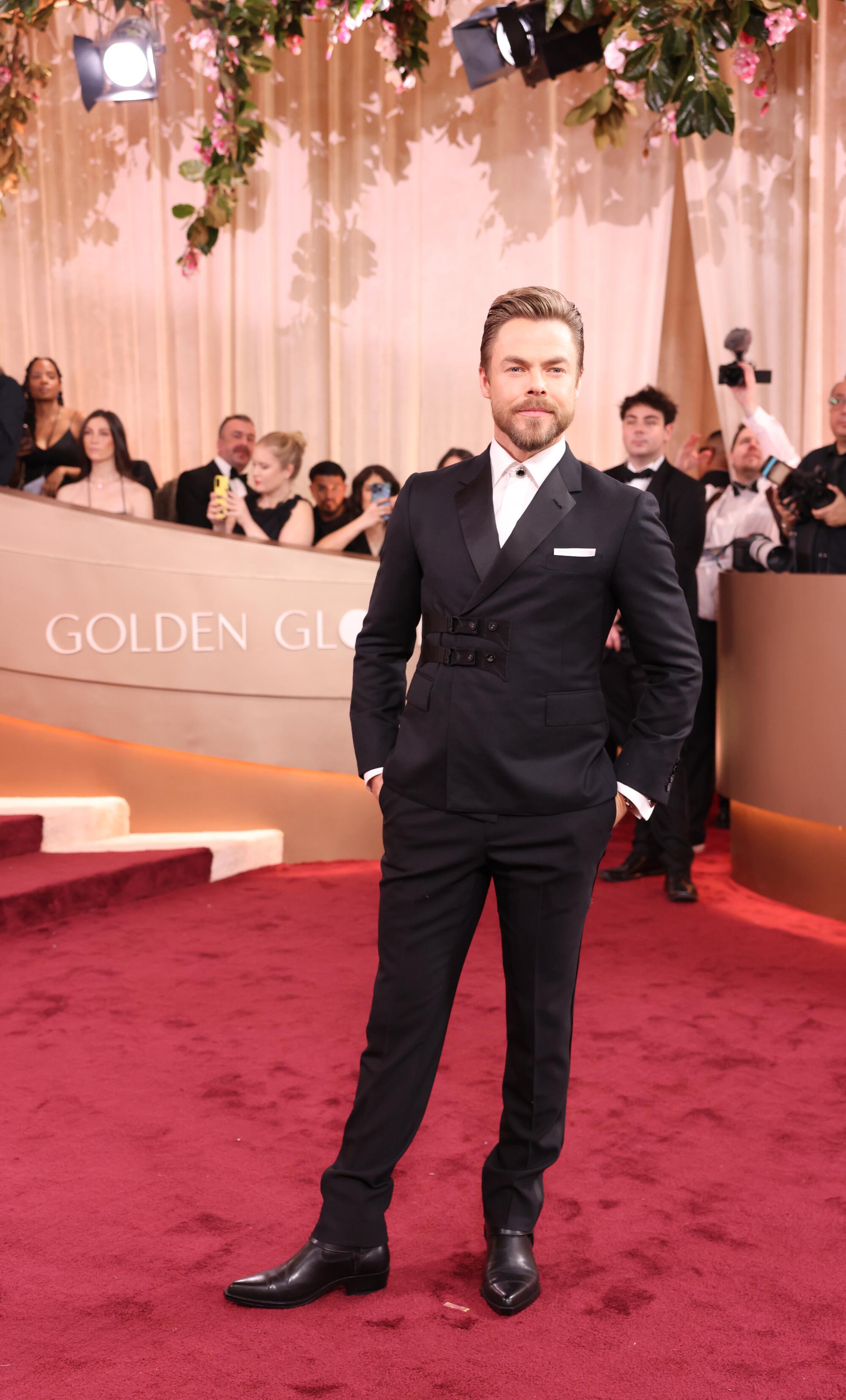 Derek Hough, in a black tux, walks the red carpet.