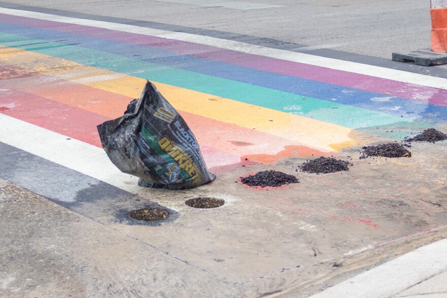 Sidewalk area is refilled with asphalt after contractors removed cylinders of the rainbow painted sidewalk.