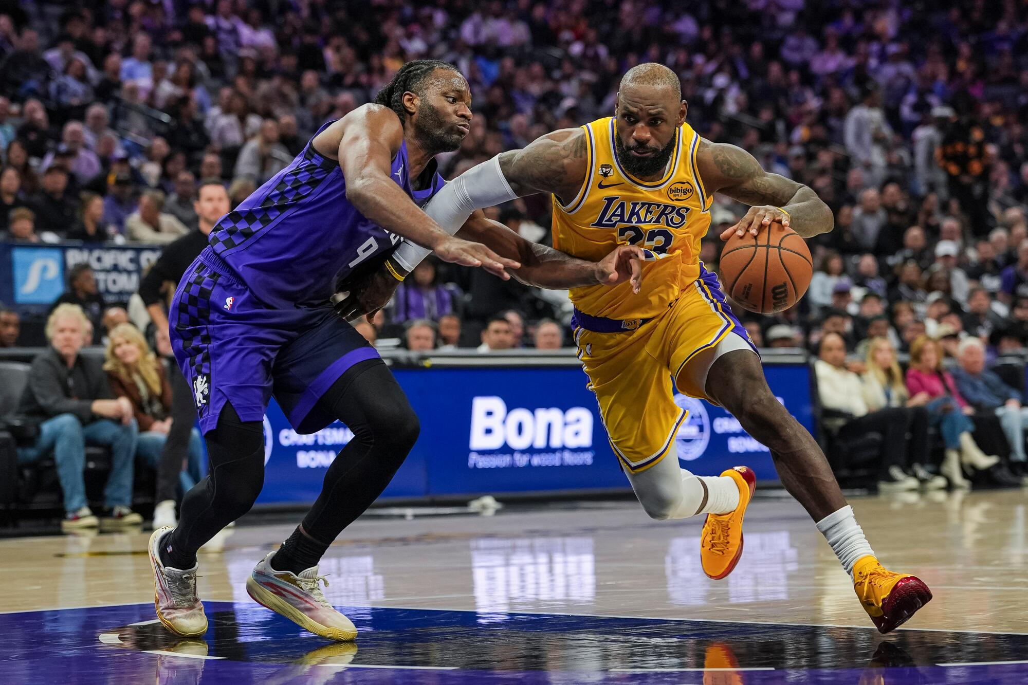 Lakers star LeBron James, right, drives against Sacramento Kings forward Precious Achiuwa.