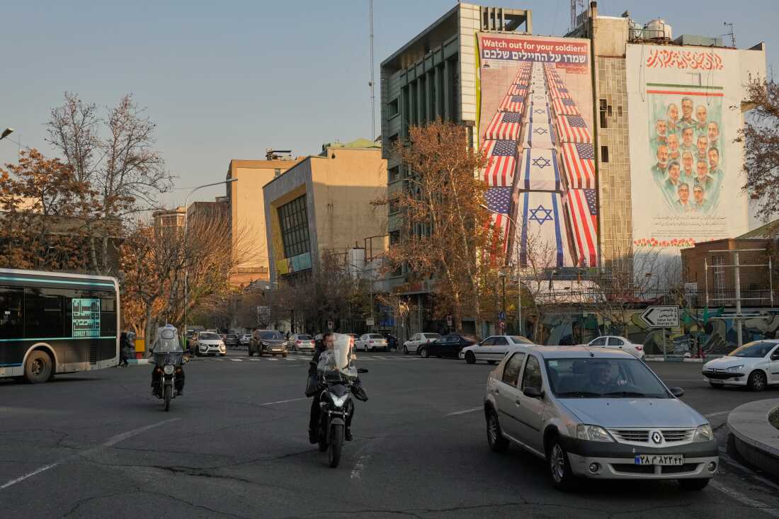 Vehicles in Tehran drive past banners with anti-U.S. and anti-Israel messages and portraits of Iranian armed forces commanders and nuclear scientists who were killed in Israeli strikes in June 2025, at the Felestin (Palestine) Square, Jan. 4.