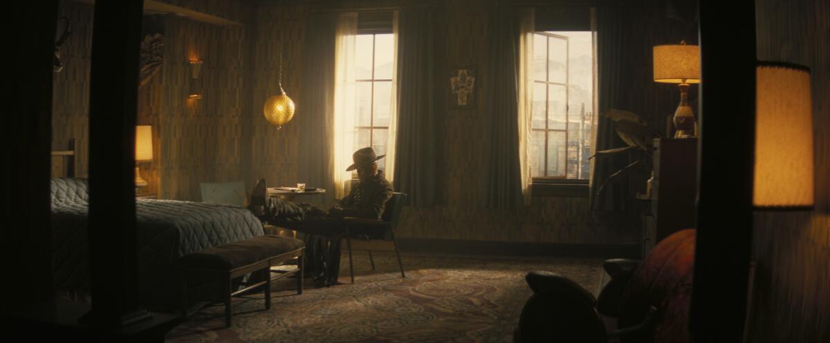 a figure sitting in a chair near a bed in a hotel room