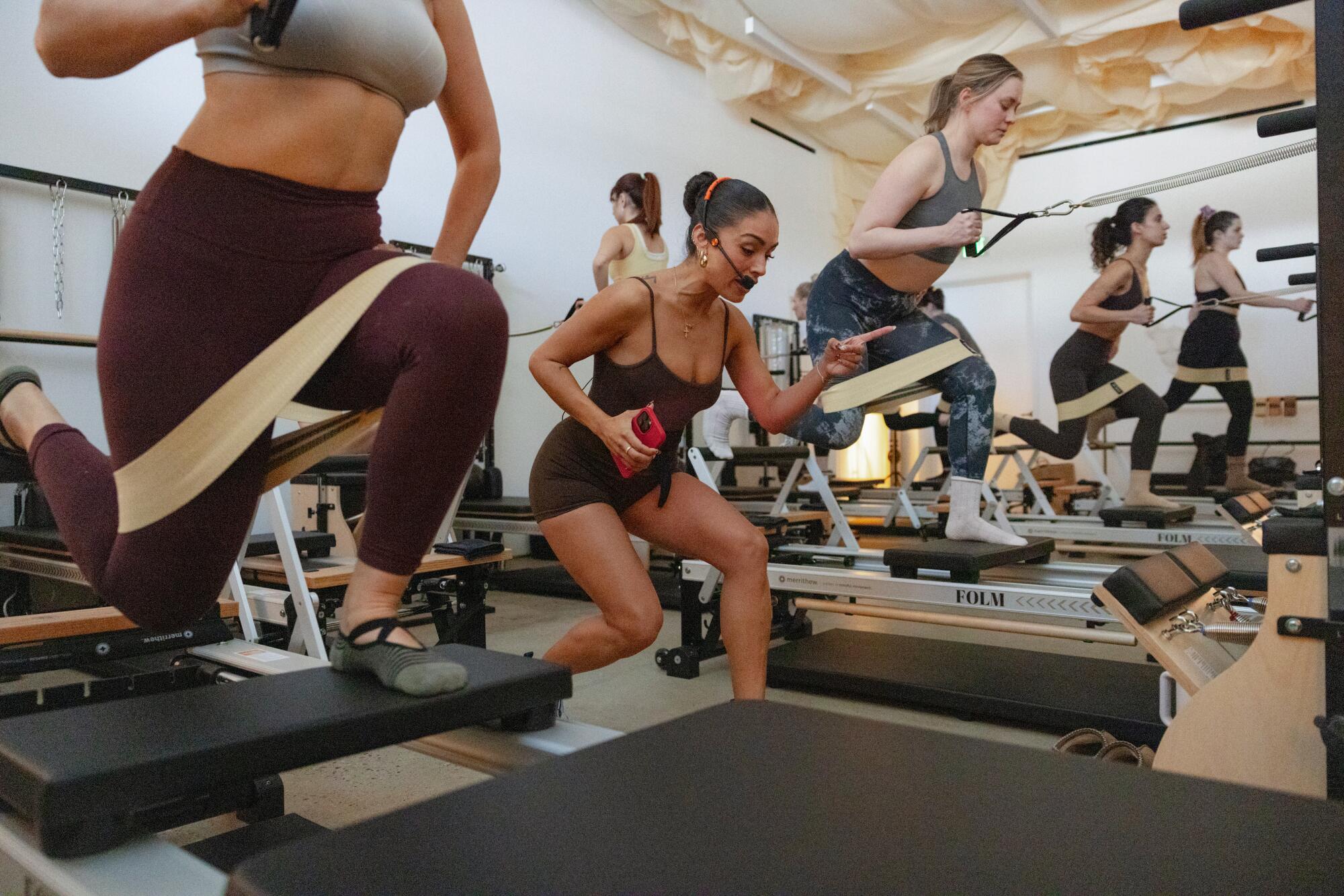 Instructor and co-founder Cindy Gomez, center, leads a reformer-based class.