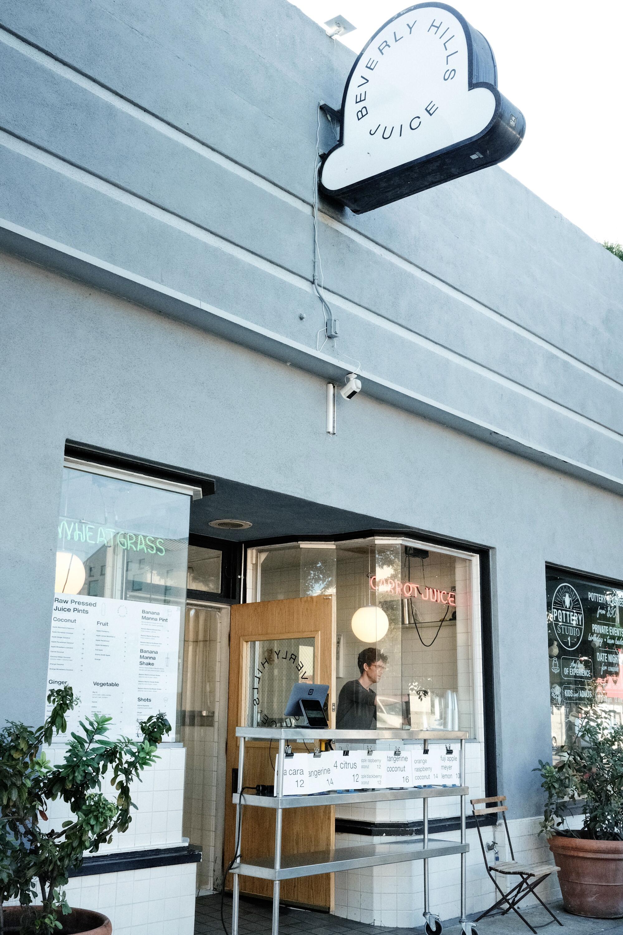 A vertical exterior of Beverly Hills Juice. An owner works in the front window.