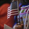 A woman clutches a U.S. flag as she and applicants from 20 countries prepare to take an oath of citizenship in commemoration of Independence Day during a naturalization ceremony in San Antonio in July 2025.