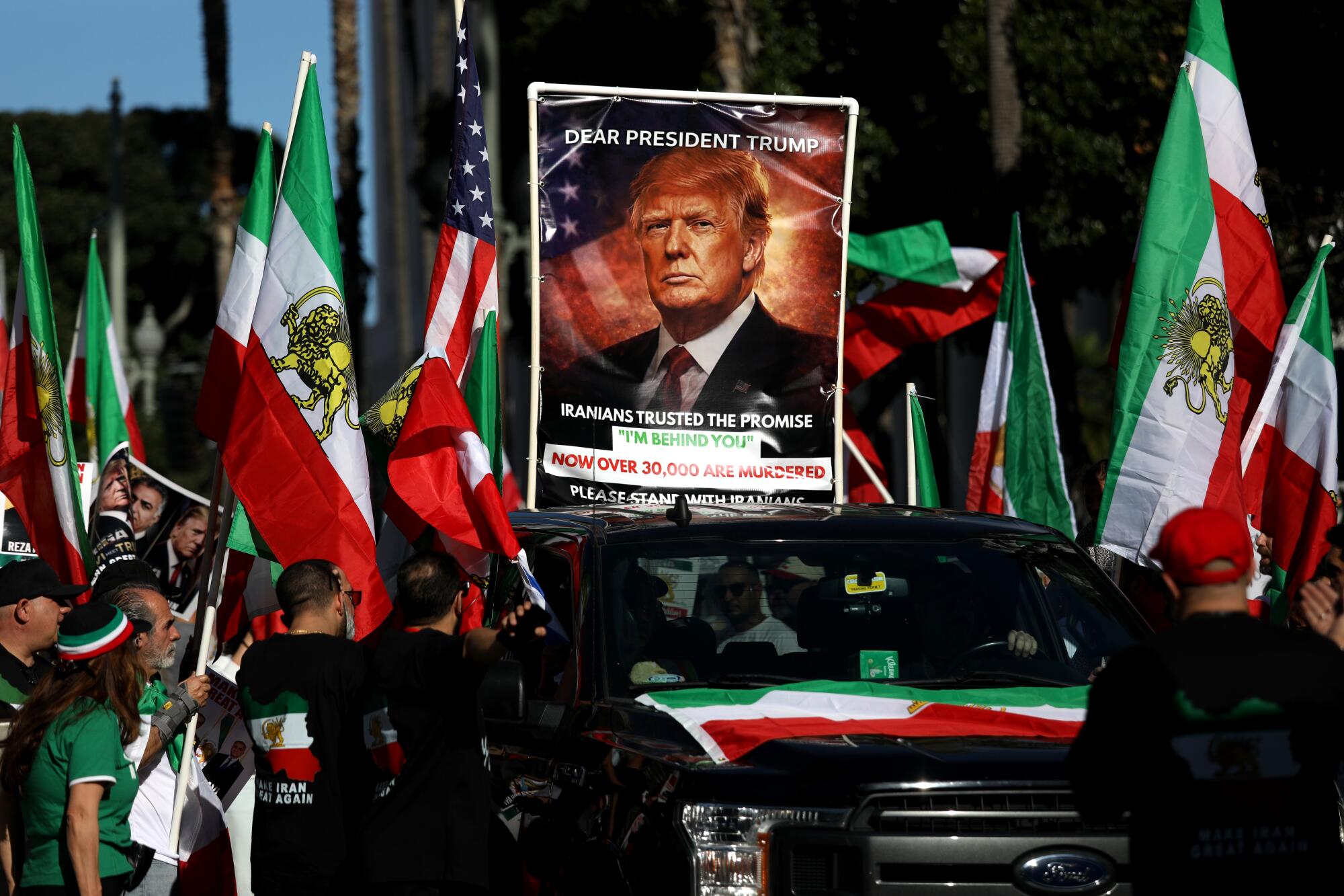 A poster picturing Donald Trump and a message is surrounded by flags at a march in downtown.