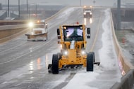 A grader plows sleet off of a bridge and entrance ramp from eastbound SH 114 to John...