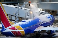 A worker sprays deicing fluid on a Southwest Airlines plane at the gates of Dallas Love...