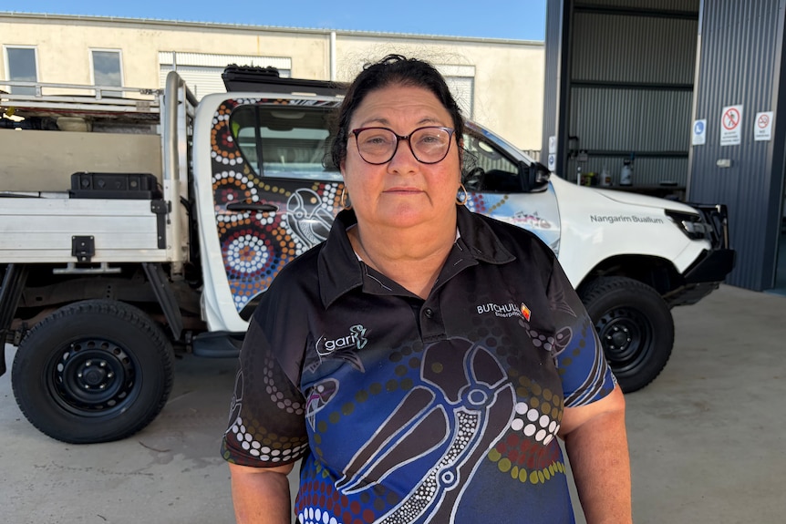 A woman in glasses standing in front of a ute