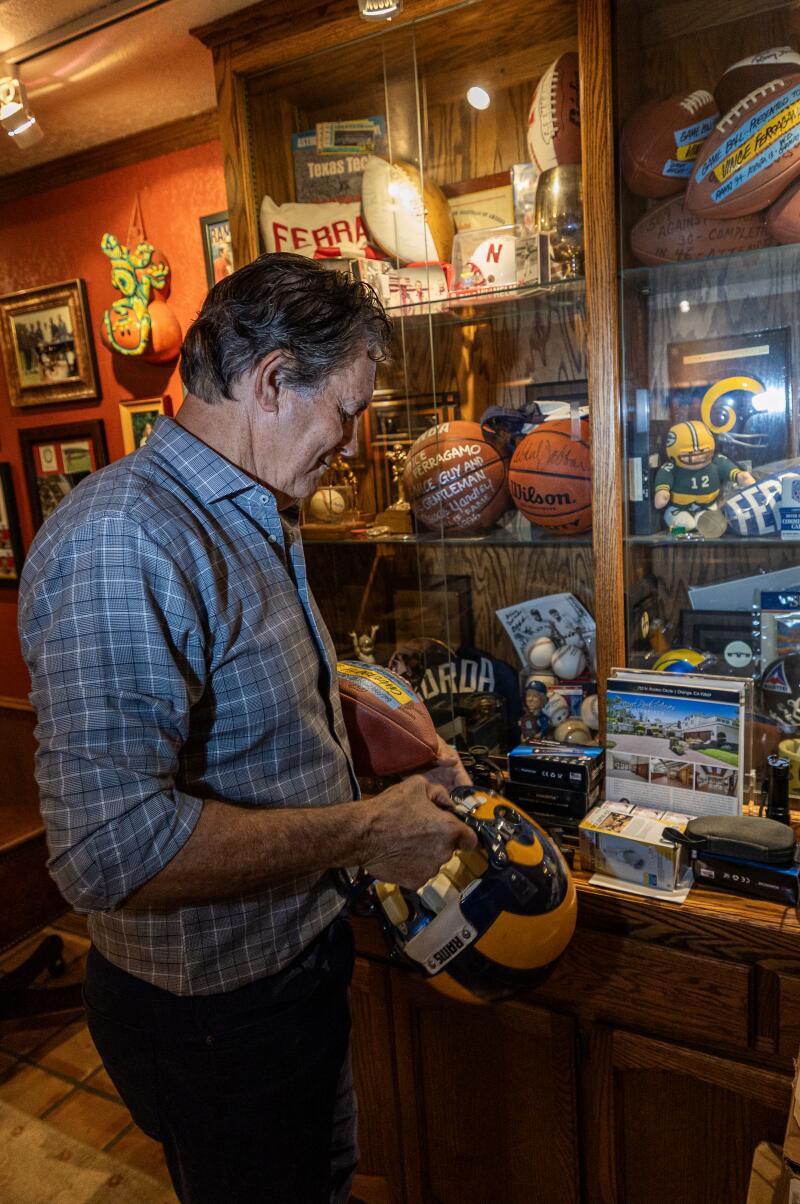 Vince Ferragamo holds his Rams quarterback helmet while viewing memorabilia from his career on display in his home.