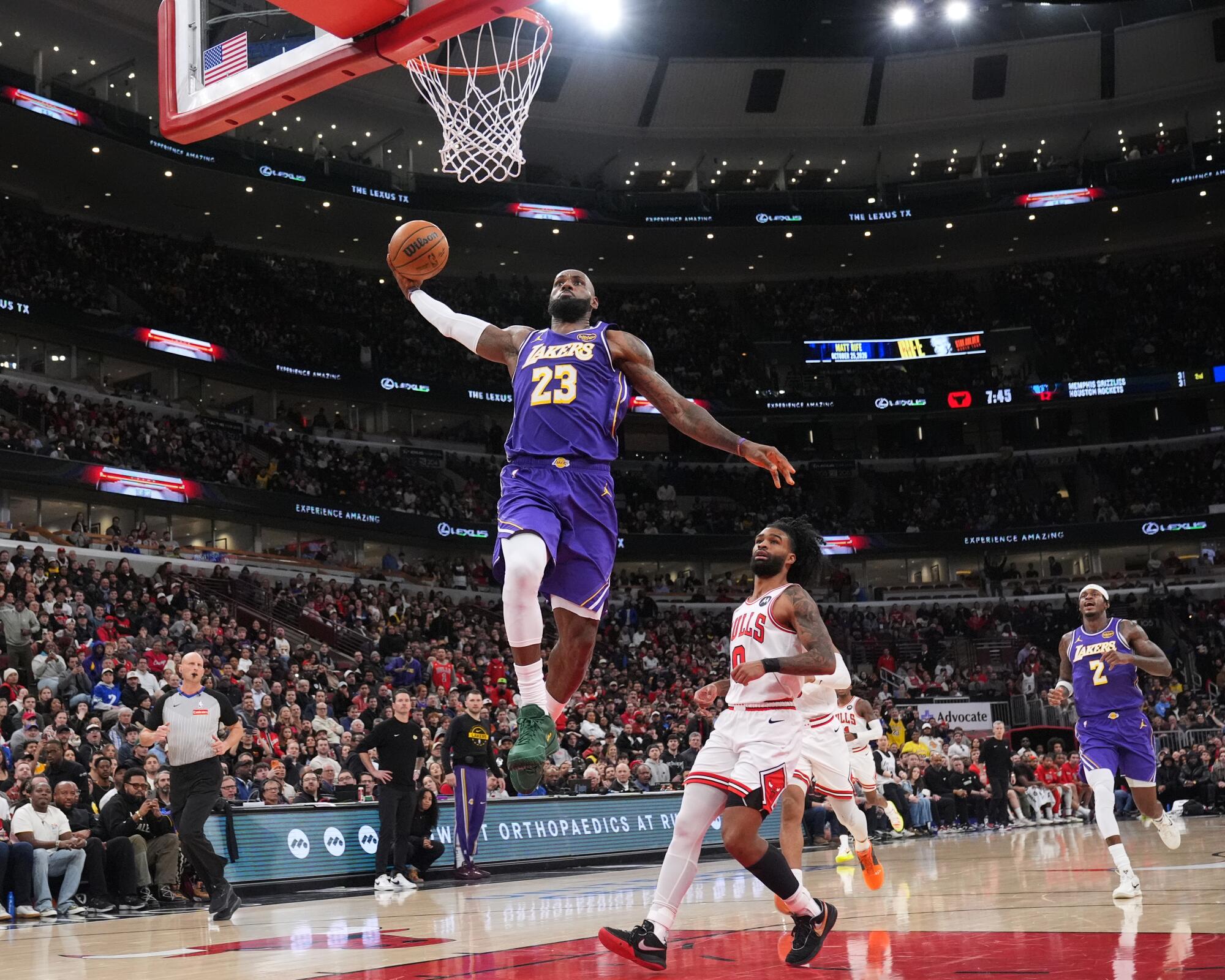 Lakers star LeBron James dunks in front of Chicago Bulls guard Coby White in the first half Monday.
