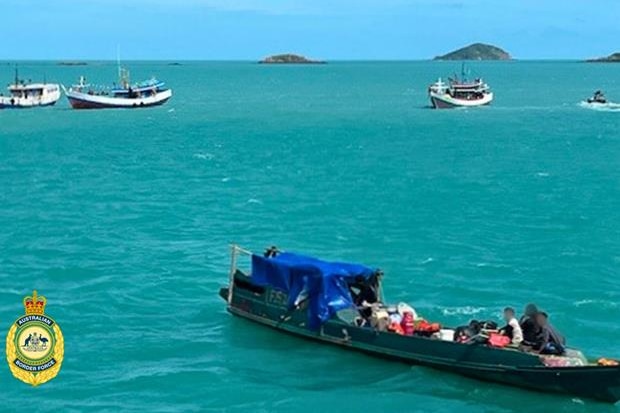 Four wooden blue boats in water.