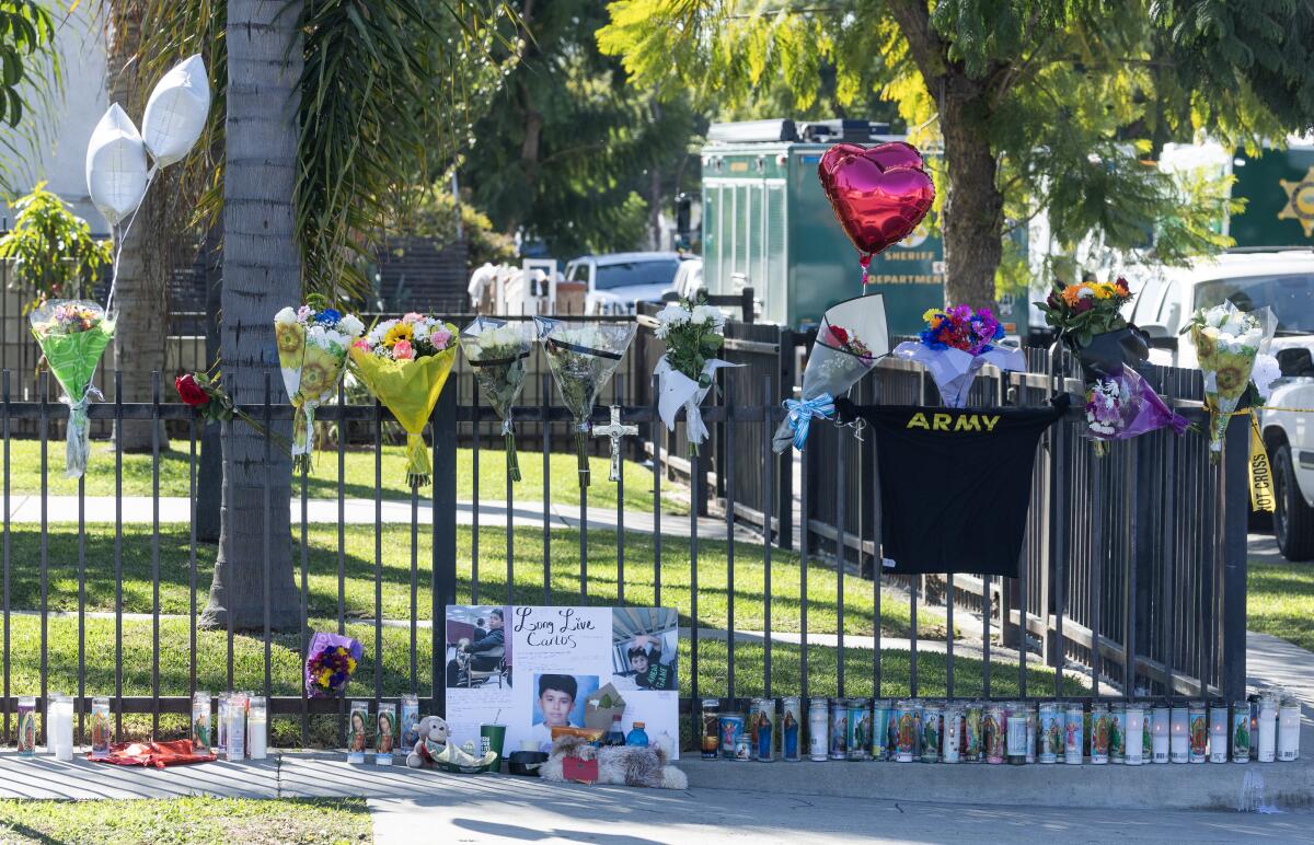 Candles along and flowers on a fence surrounding a yard.