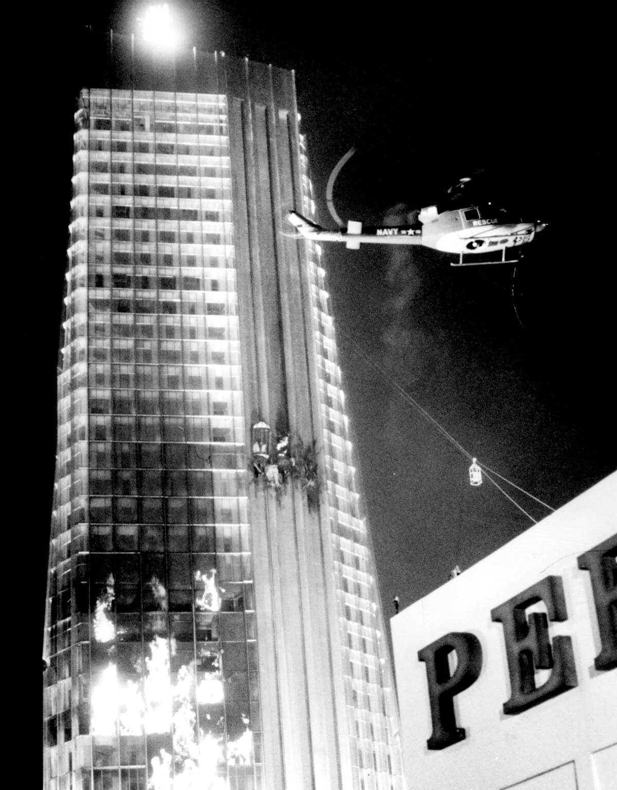 A helicopter hovers next to a burning skyscraper.