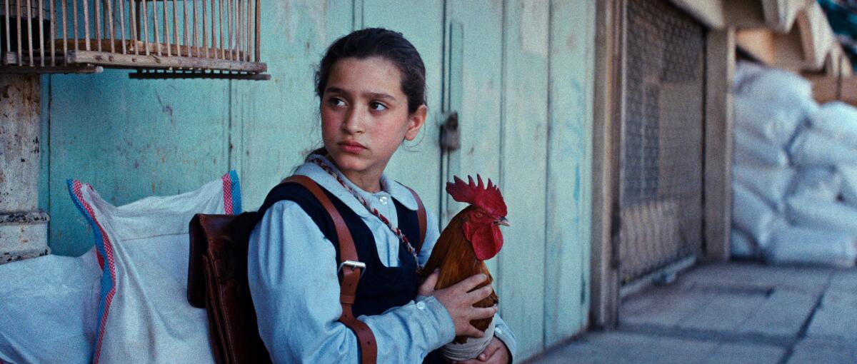 A woman sits with a rooster.