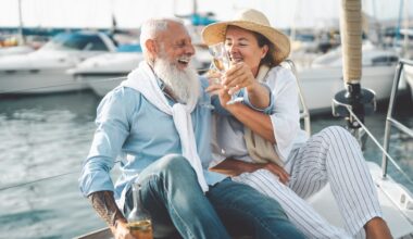 Senior couple toasting champagne on sailboat vacation - Happy elderly people having fun celebrating wedding anniversary on boat trip - Love relationship and travel lifestyle concept.