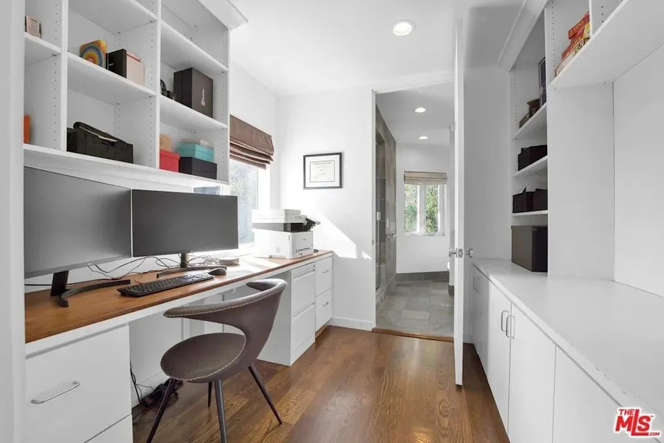 The private office features built-in cabinetry, shelving and desks, in addition to a window with a remarkable view.