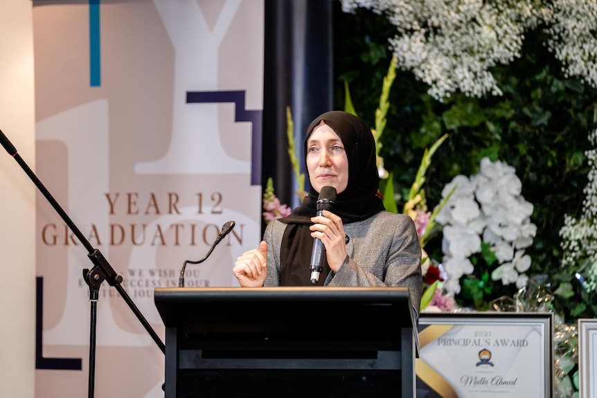 A woman speaking behind a lectern 