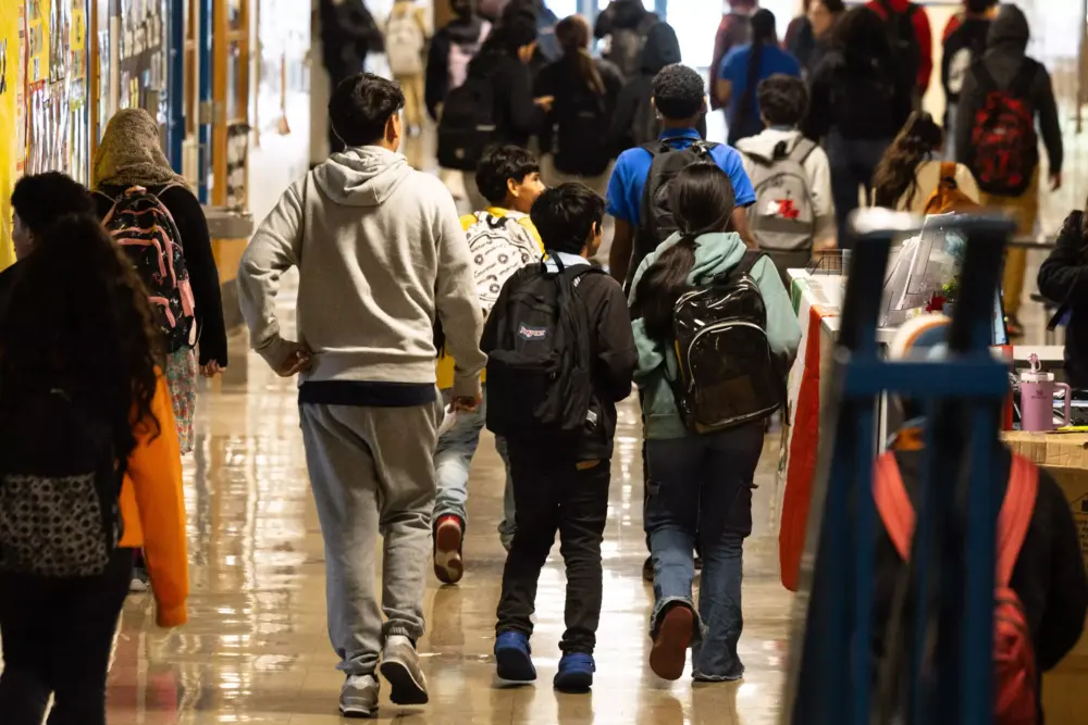 Webb Middle School students walk to class on Nov. 12, 2024. Children of various ages are seen walking through the hallway, wearing backpacks.  