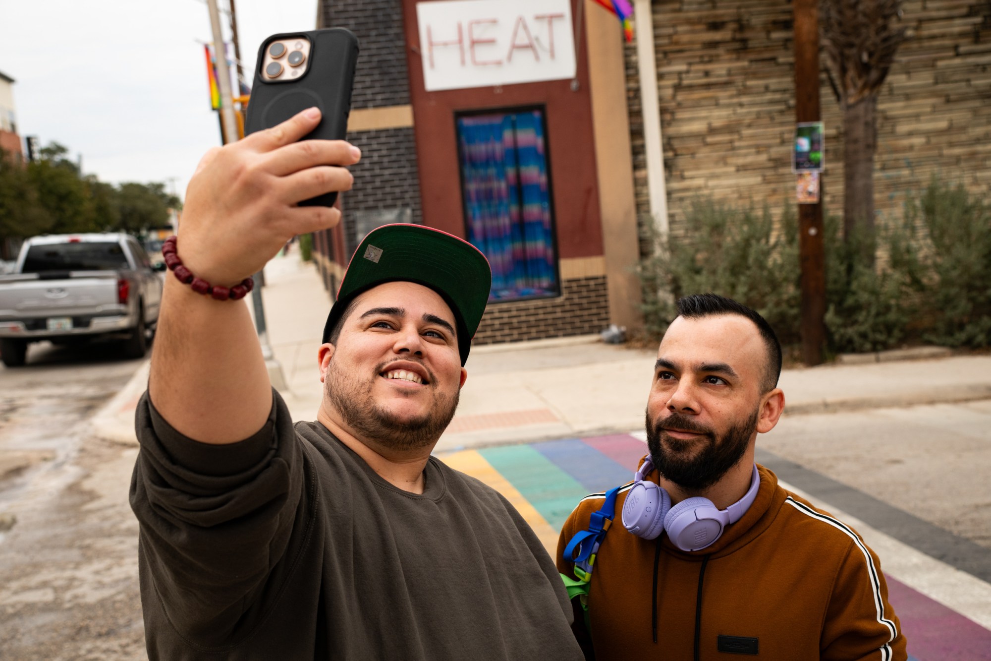 Alex Sanchez, left, and Jeancarlo Garcia, right, take a selfie with the rainbow crosswalk as construction workers begin the removal process in San Antonio.