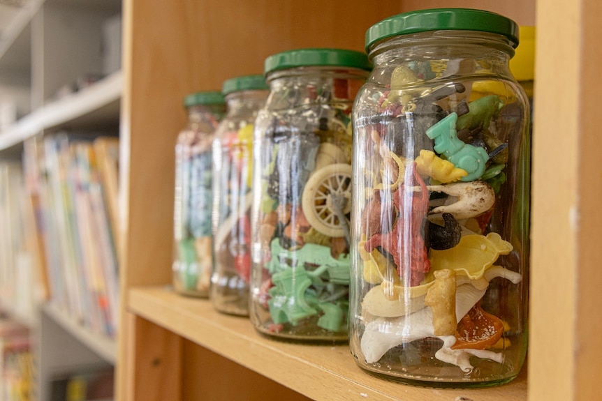 Four jars sits on a self with coloured plastic objects.