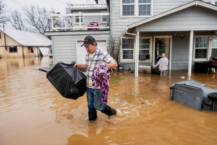 Steve Wogoman carries Christmas presents from his granddaughter's flooded home following heavy rains, on Monday, Dec. 22, 2025, in Redding, Calif. 