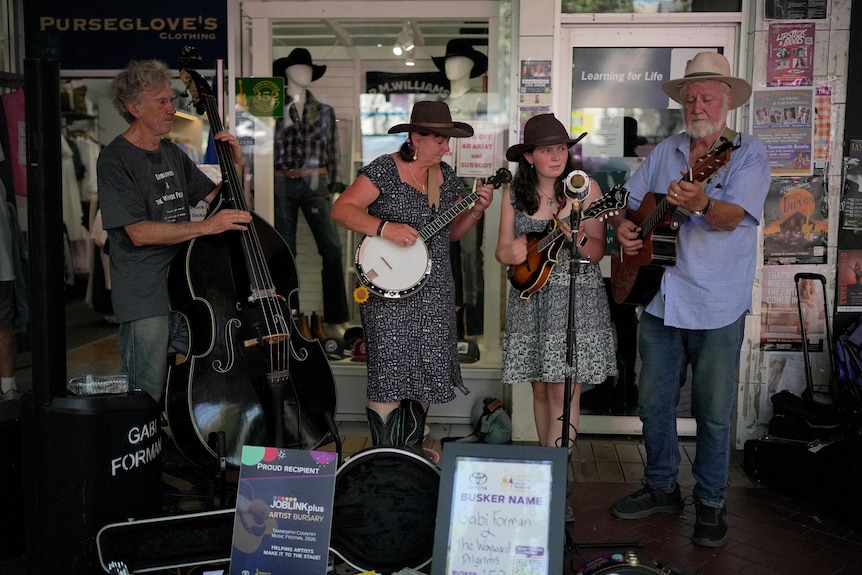 Two women and two men busk together on a footpath.