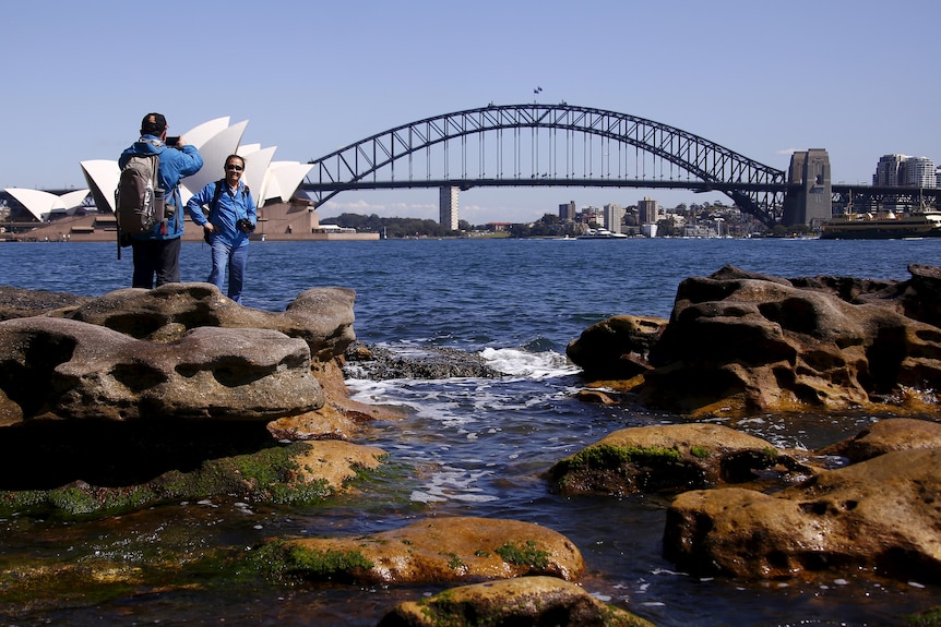two man taking photos in front of Opera House and Sydney Harbor Bridge