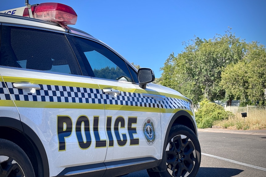 An SA police car parked on the side of a street with trees on the opposite side