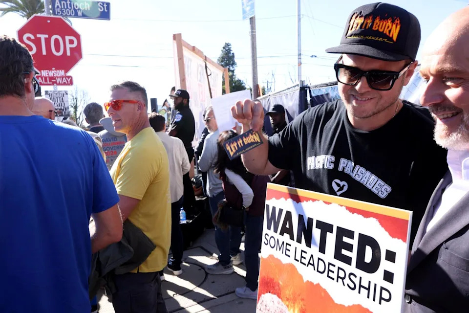 Palisades resident Spencer Pratt with another man holding a sign saying wanted: some leadership.