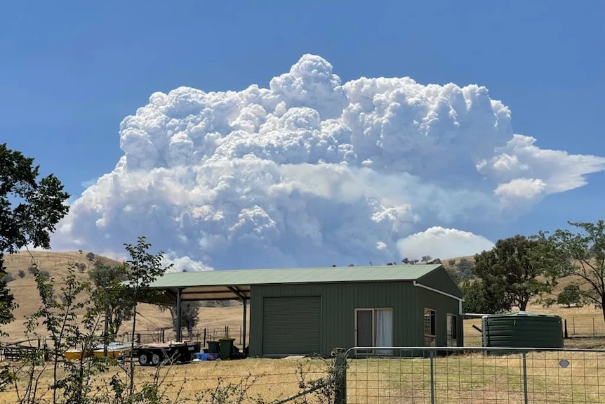 A cloud forms above a fire over a hill.