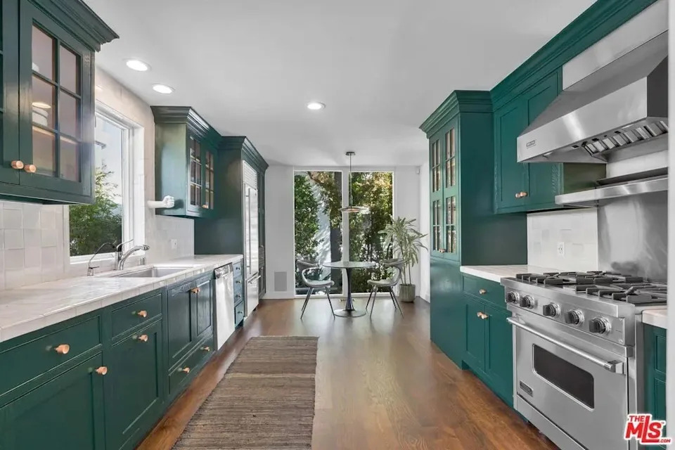 The dine-in kitchen with top of the line stainless steel appliances and rich emerald cabinetry blends modern convenience with classic design.