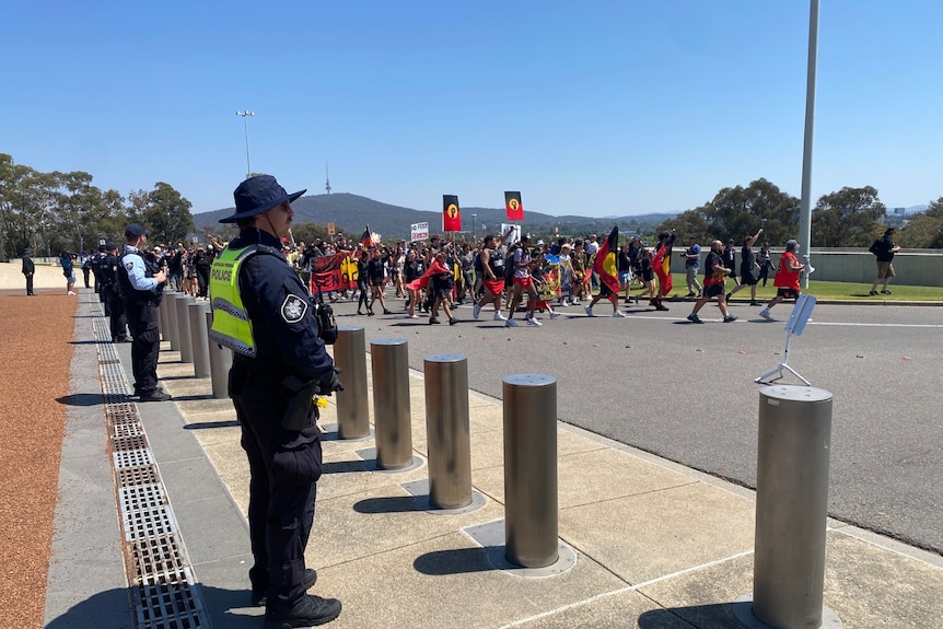 A group of people with flags and signs walking down road