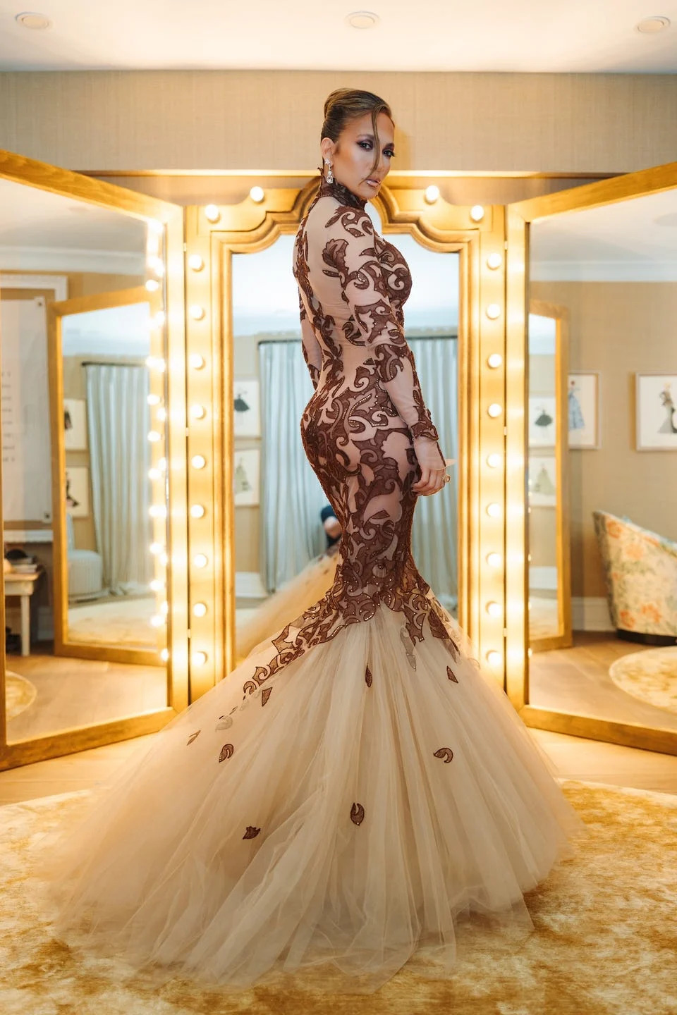 model wearing a formal gown in front of mirrors and bright lights