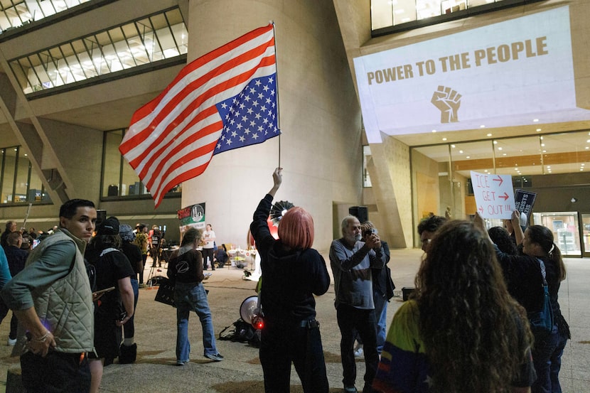 A demonstrator raises an upside down American flag during an ‘ICE Out Now’ protest outside...