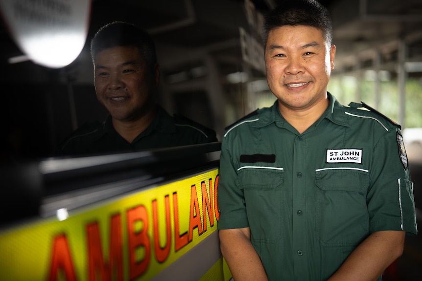 Dr Felix Ho stands next to an ambulance dressed in his paramedic's uniform.