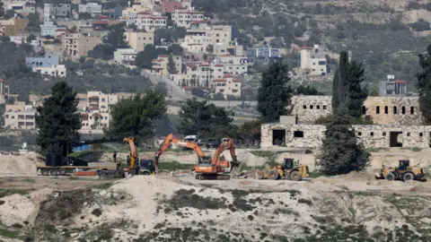EPA Israeli bulldozers level land at the evacuated Israeli settlement of Sanur, near Jenin, in the occupied West Bank (23 December 2025)