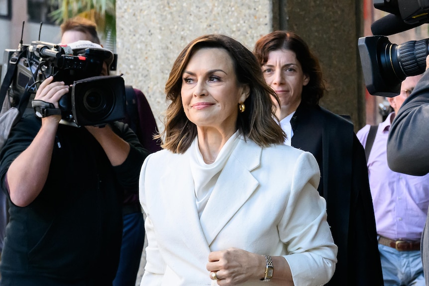 Lisa Wilkinson smiling enters Federal Court in Sydney before Bruce Lehrmann defamation judgment, media around