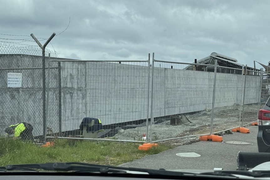 A concrete wall surrounded by scaffolding and construction materials.