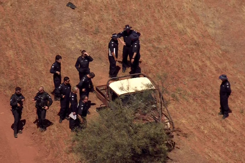 A group of police officers confer during the ongoing manhunt.