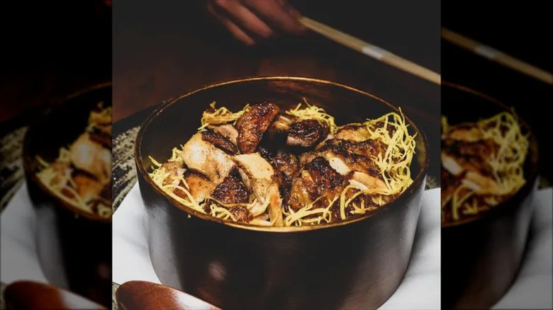 Habachi chicken over a bed of rice served in a black ceramic bowl