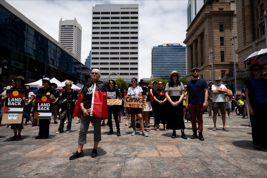 A line of people wearing flags stand in a line in a public square