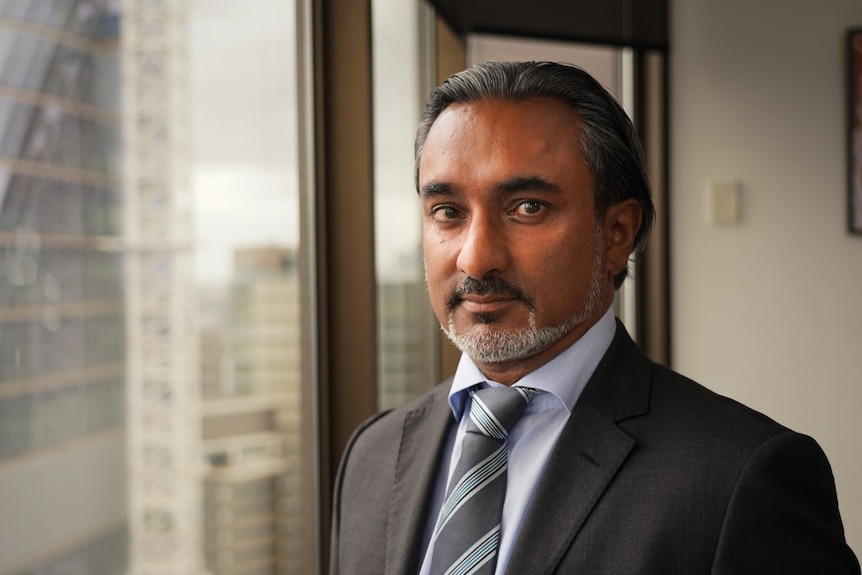 A man in a suit stares at the camera.